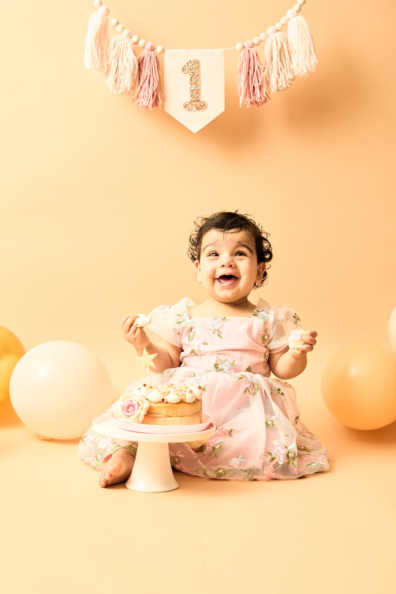 One-year-old laughing with both hands in her cake, icing everywhere, during an in-home cake smash session in South-East Melbourne