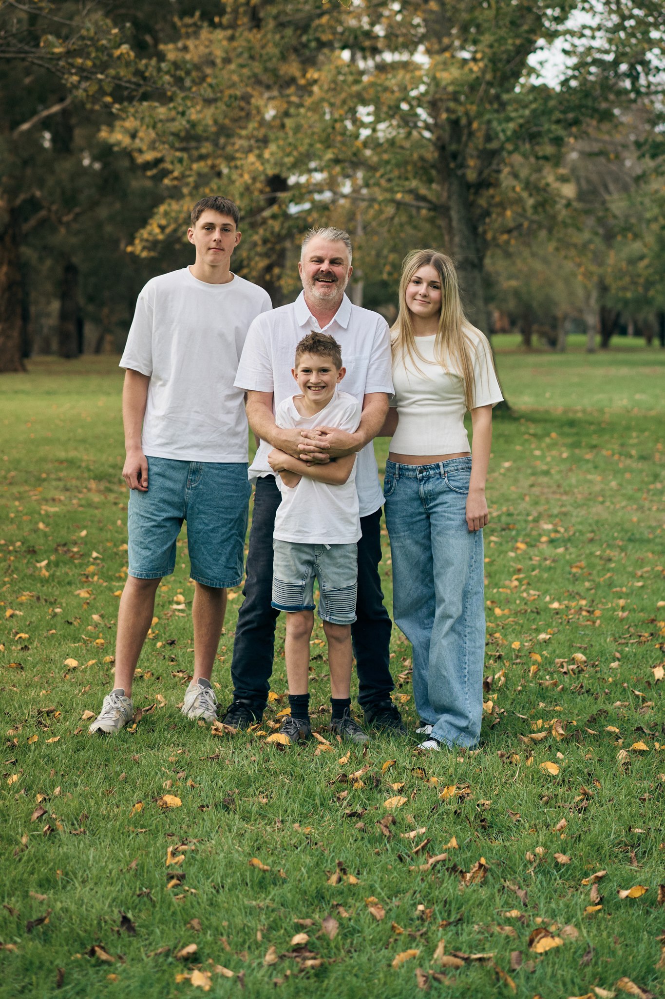 A family standing together among the trees at golden hour, outdoor family session South-East Melbourne