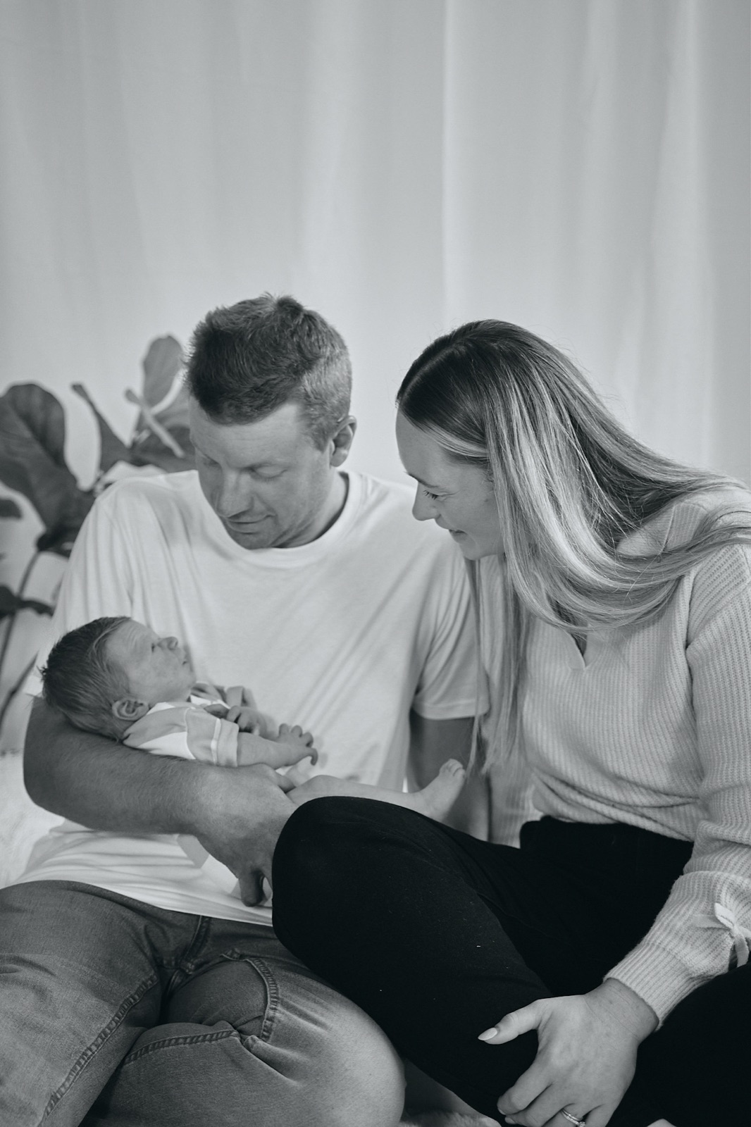 Dad kissing mum's head as she cradles their baby