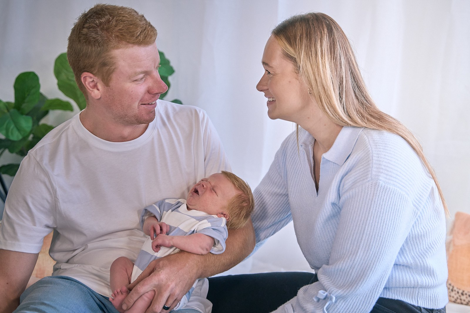 New parents smiling at each other while dad cradles their newborn