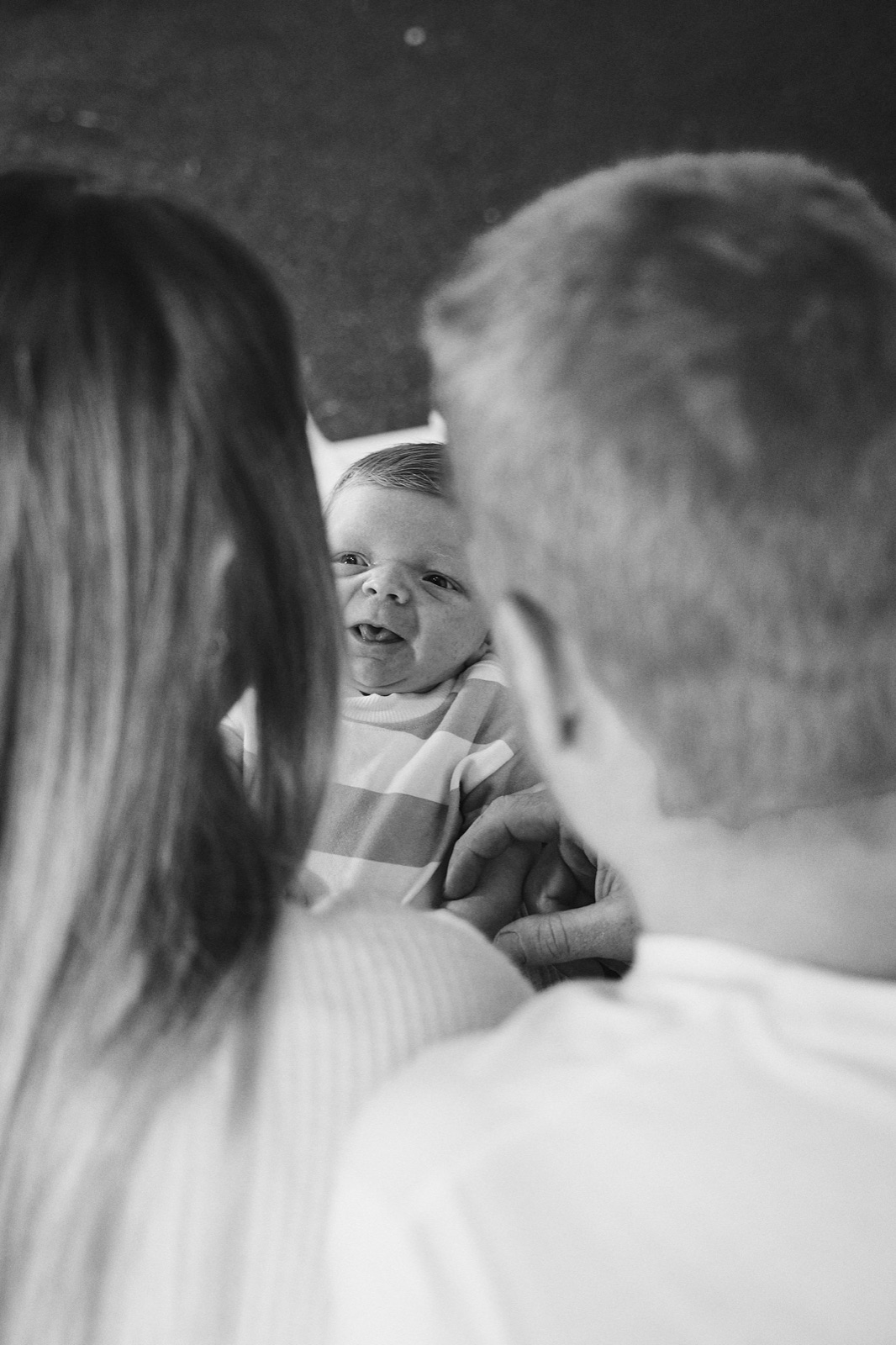 Black and white candid of parents at home with their baby
