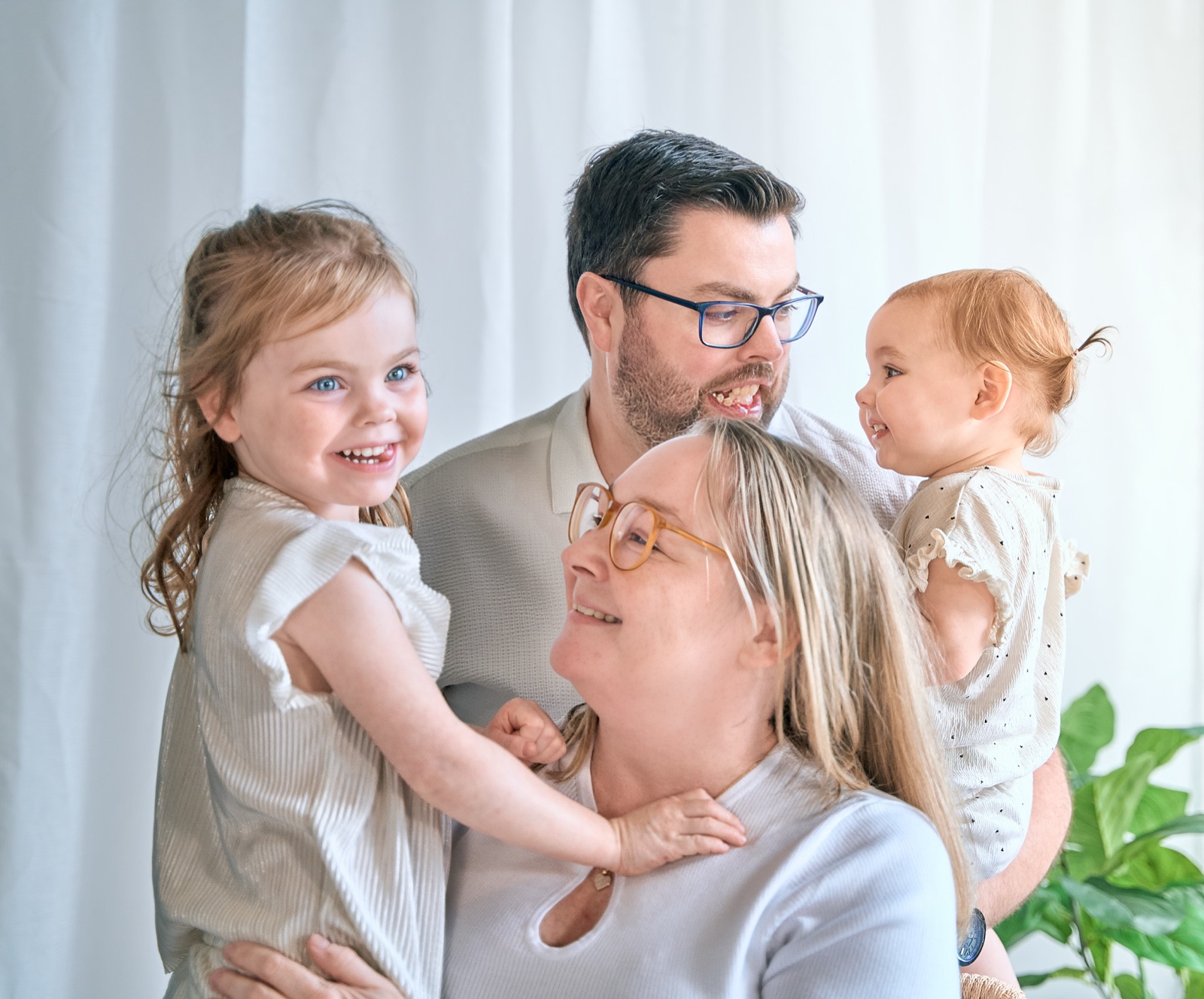 Family of four squeezed together on the couch with their baby