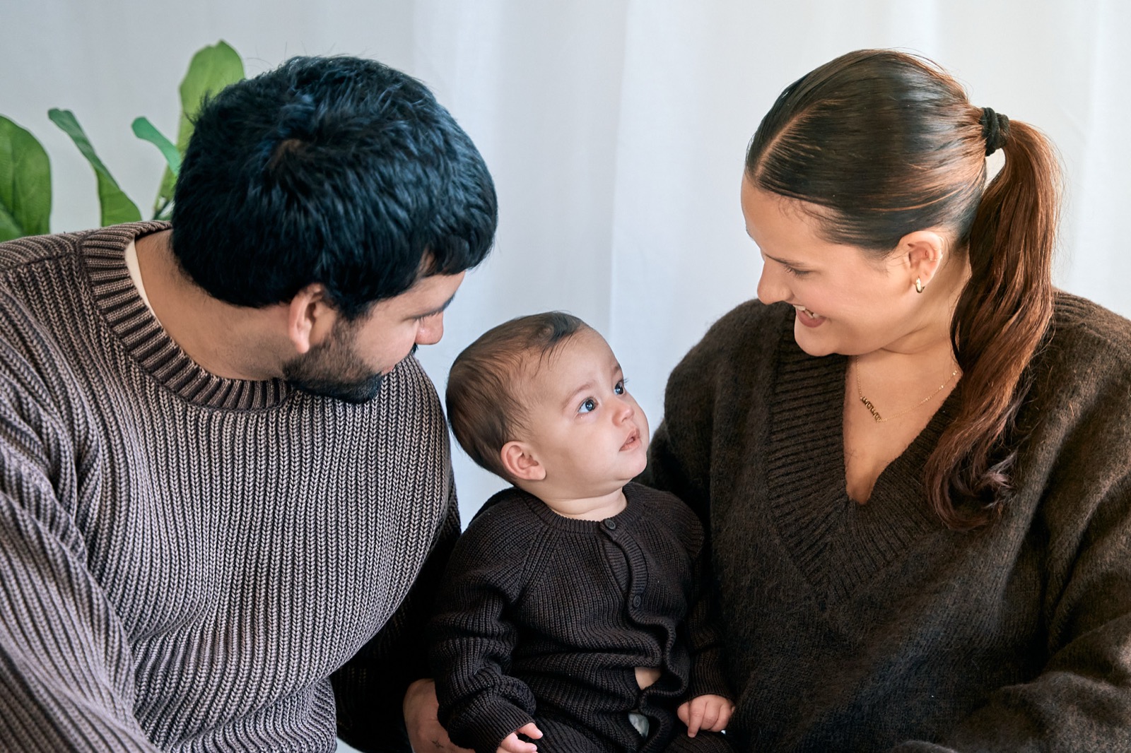 Mum and dad kissing their toddler's cheeks, playful in-home family photo