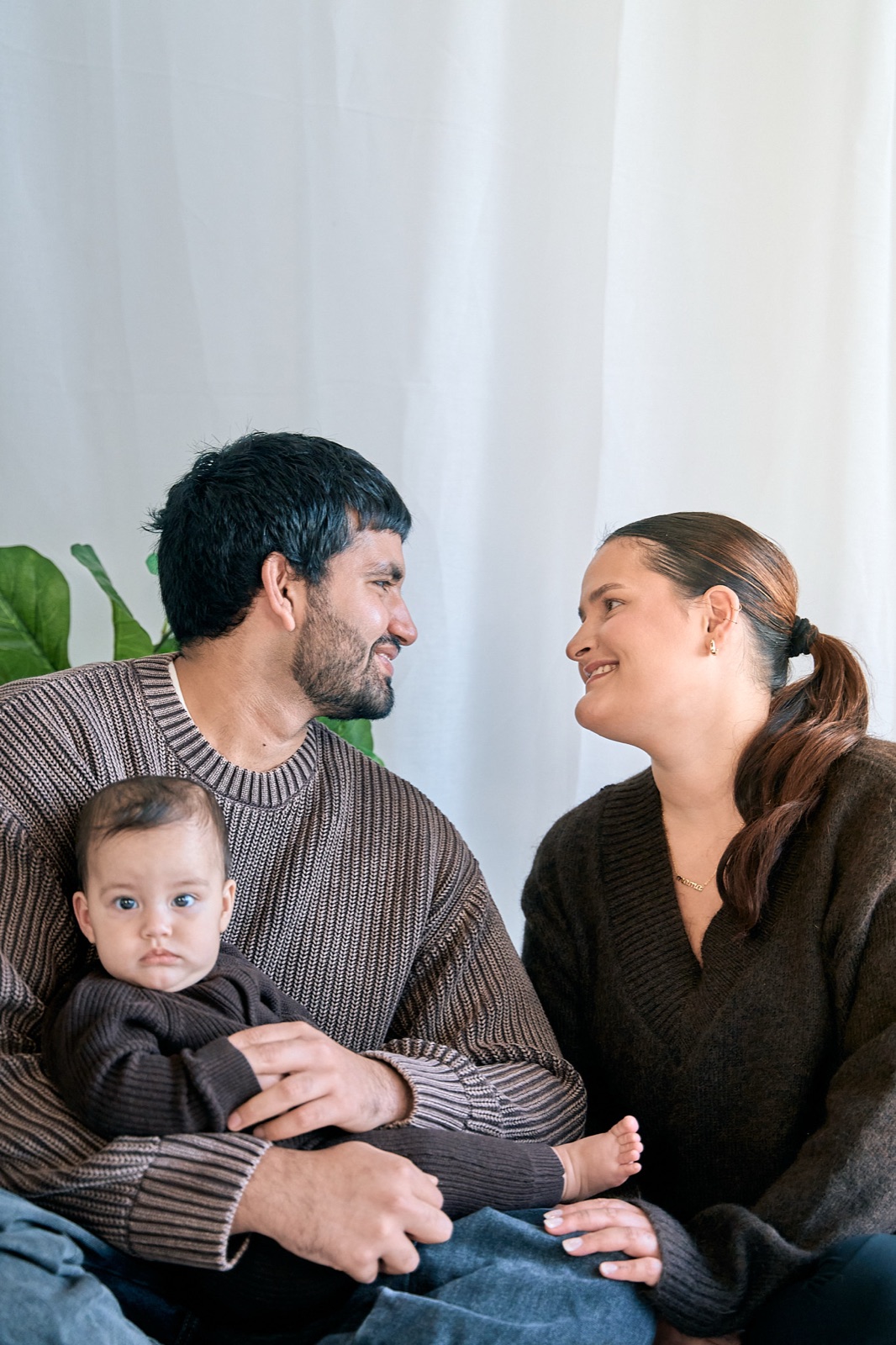 Couple sitting close with their baby on the couch