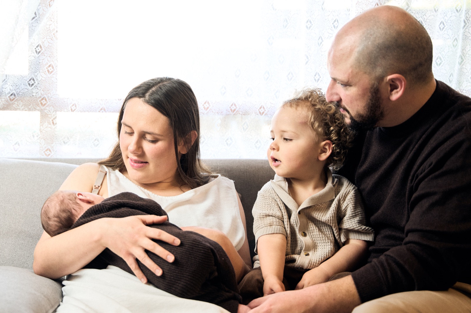 Mum holding the newborn while her toddler snuggles in close