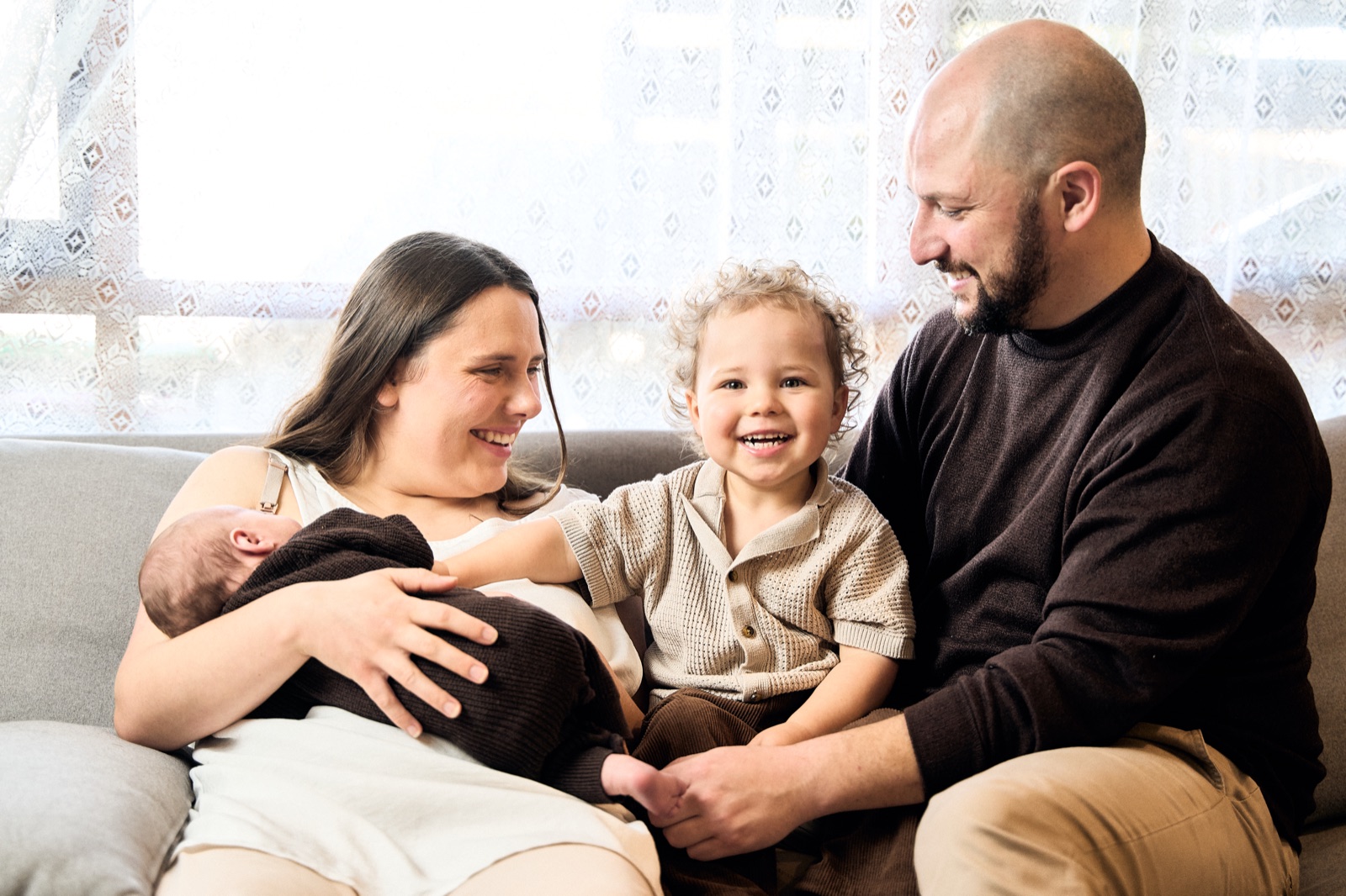Parents on the couch soaking up their newborn, in-home newborn and family session