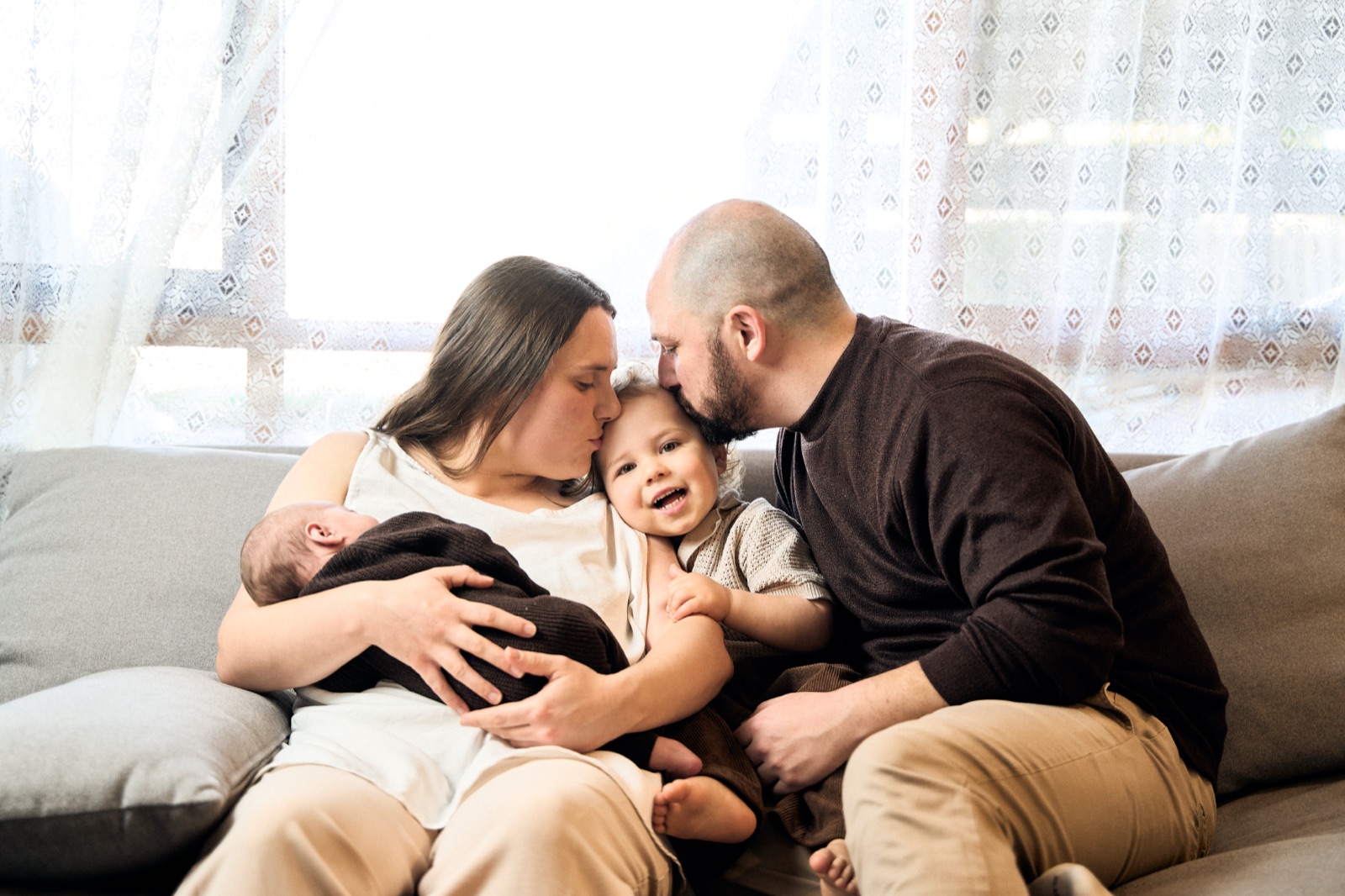 New parents on the couch with their newborn during an in-home session