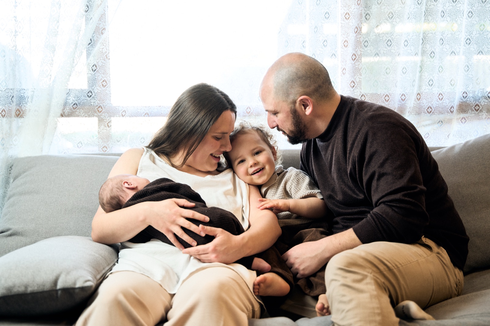 Couple sitting together with their newborn during a lounge-room session
