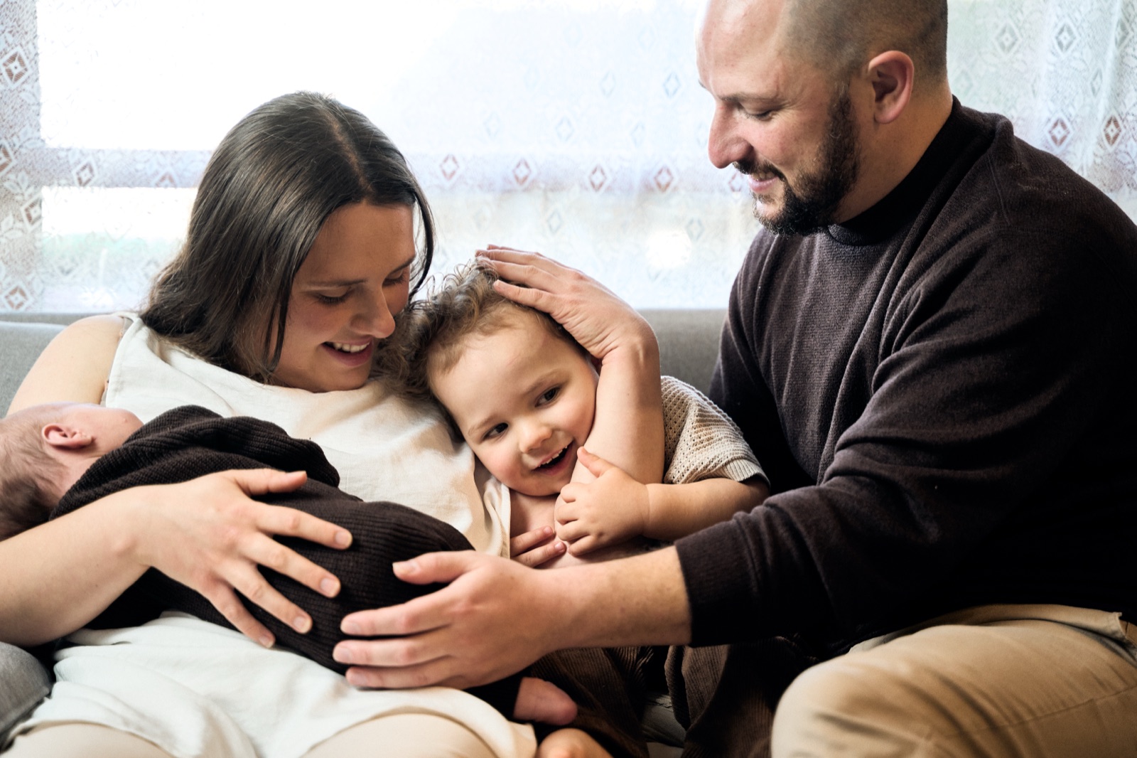 Family on the couch with their newborn, candid in-home photography