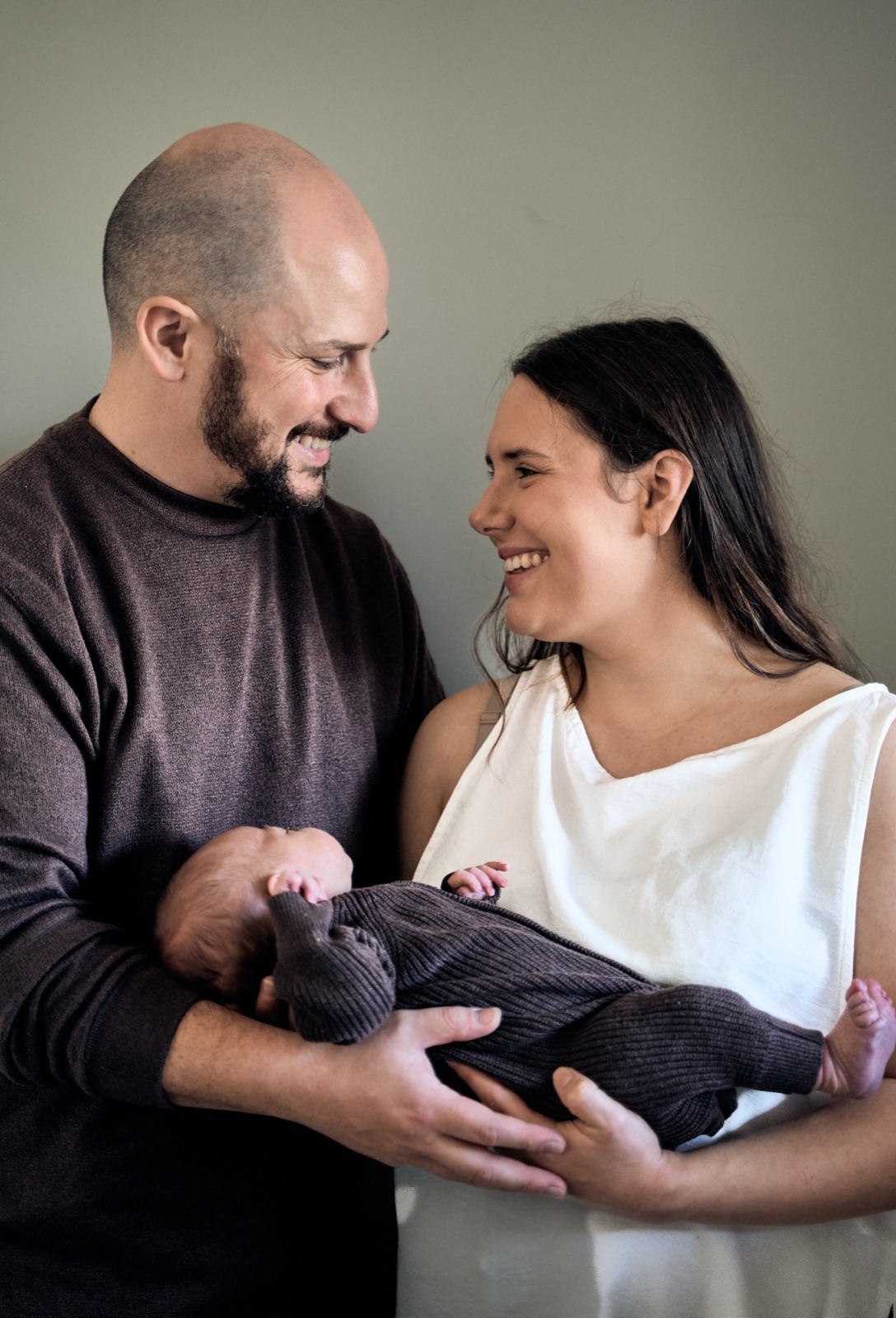 Mum and dad standing together cradling their newborn at home