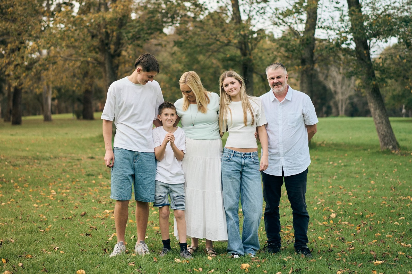 Family of five standing together under autumn trees in a Melbourne park