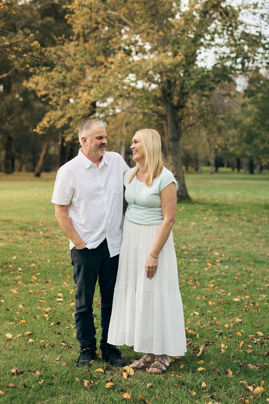 Mum and dad standing together under the autumn trees