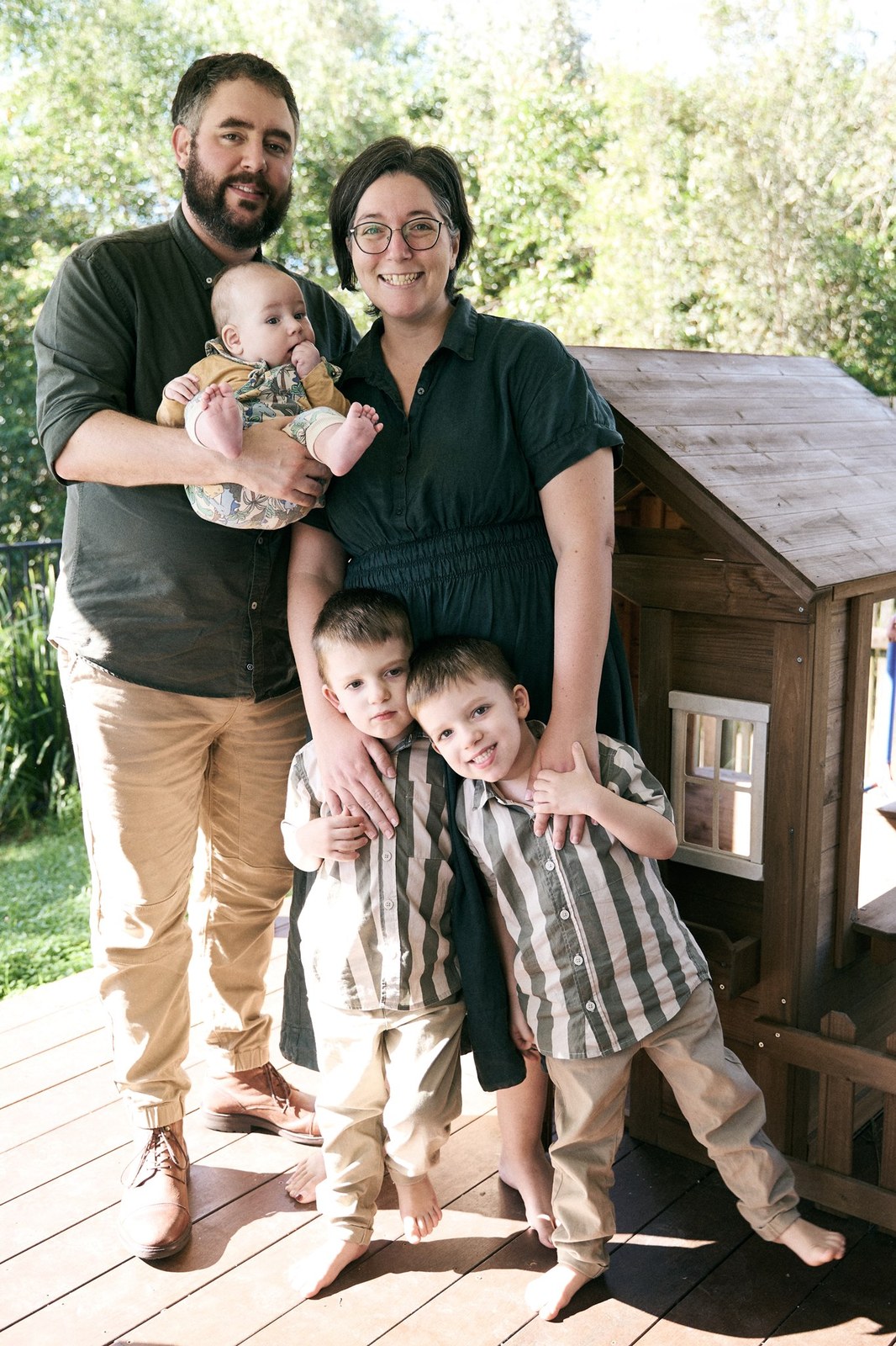 Parents holding their baby with two young sons in the back garden