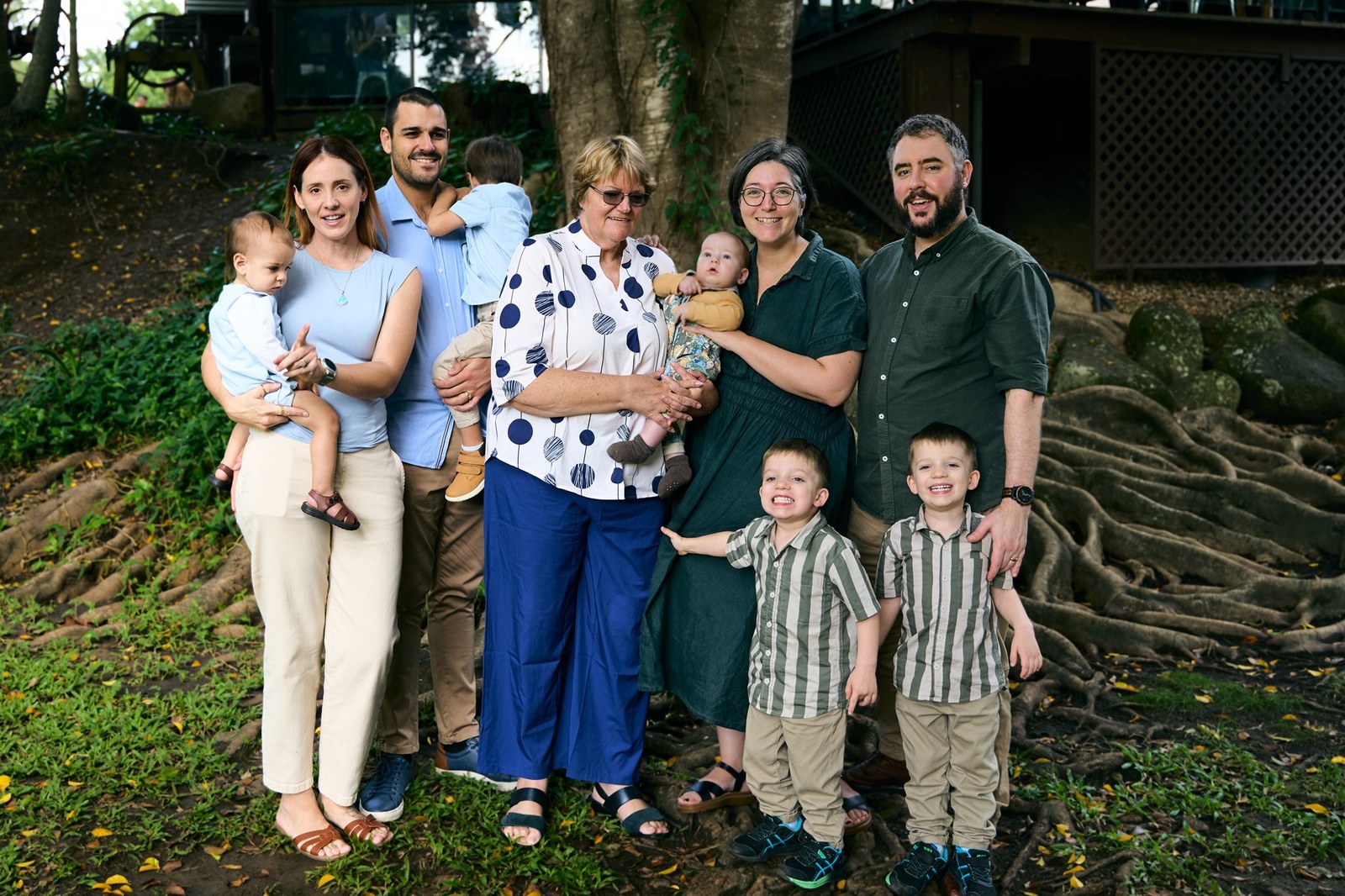 Extended family gathered among the roots of a large fig tree