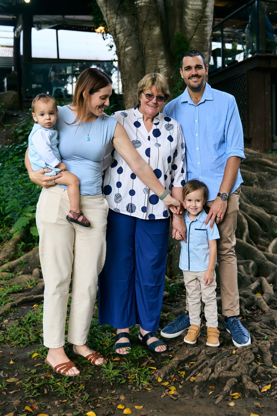 Grandparents, parents, a baby and a toddler under the tree together