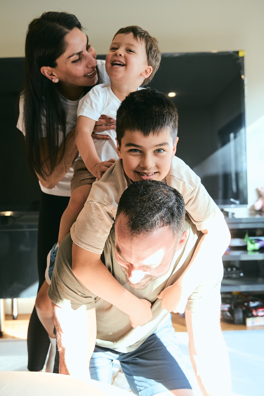 Mum and two boys piling onto dad in the lounge room