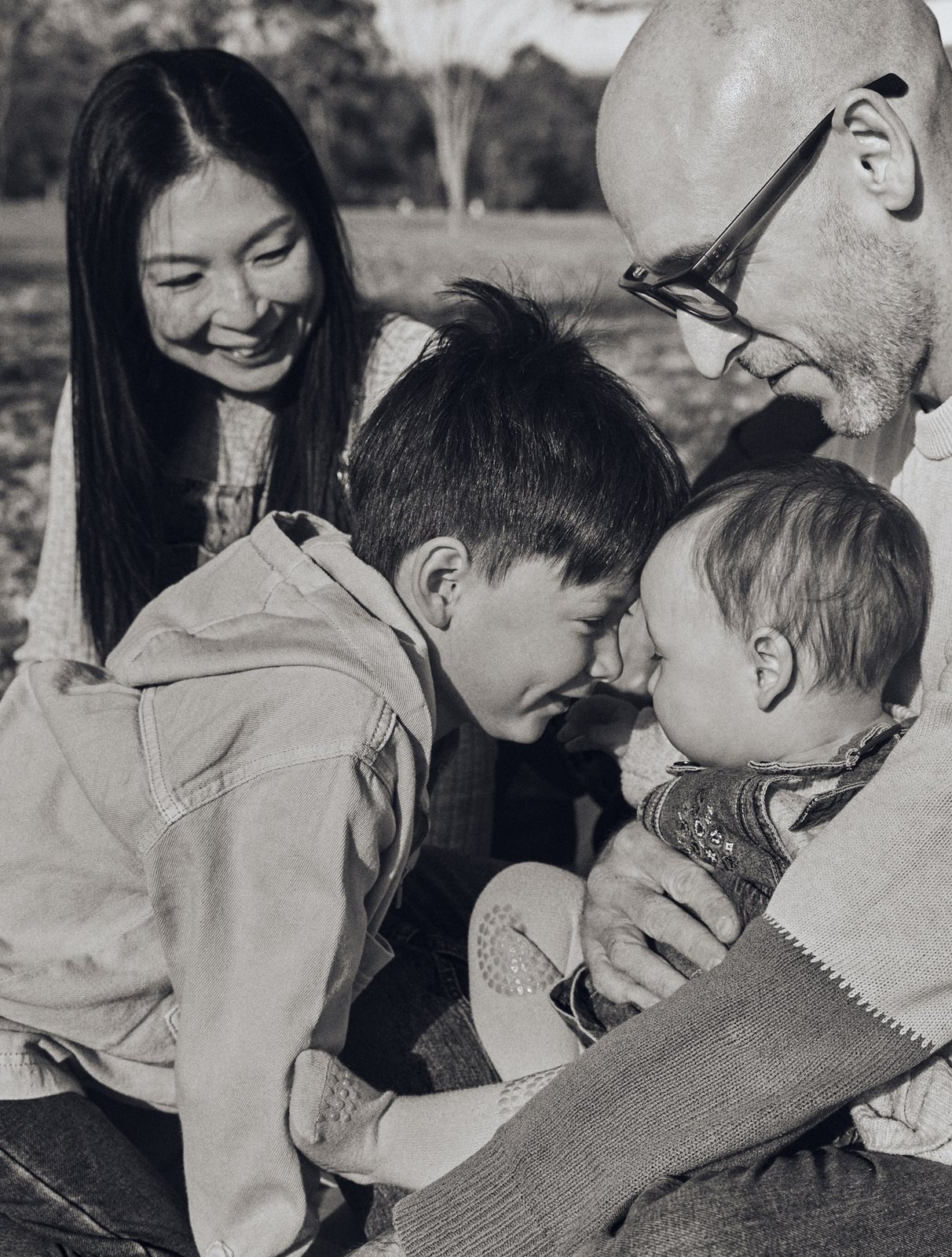 Black and white portrait of parents huddled close with their two boys
