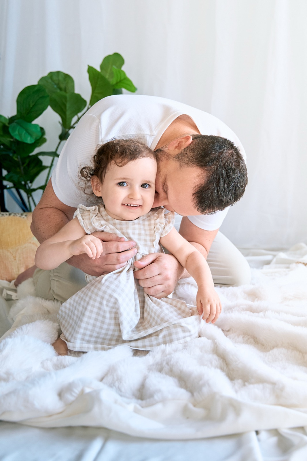 Dad on the bed playing with his two young daughters