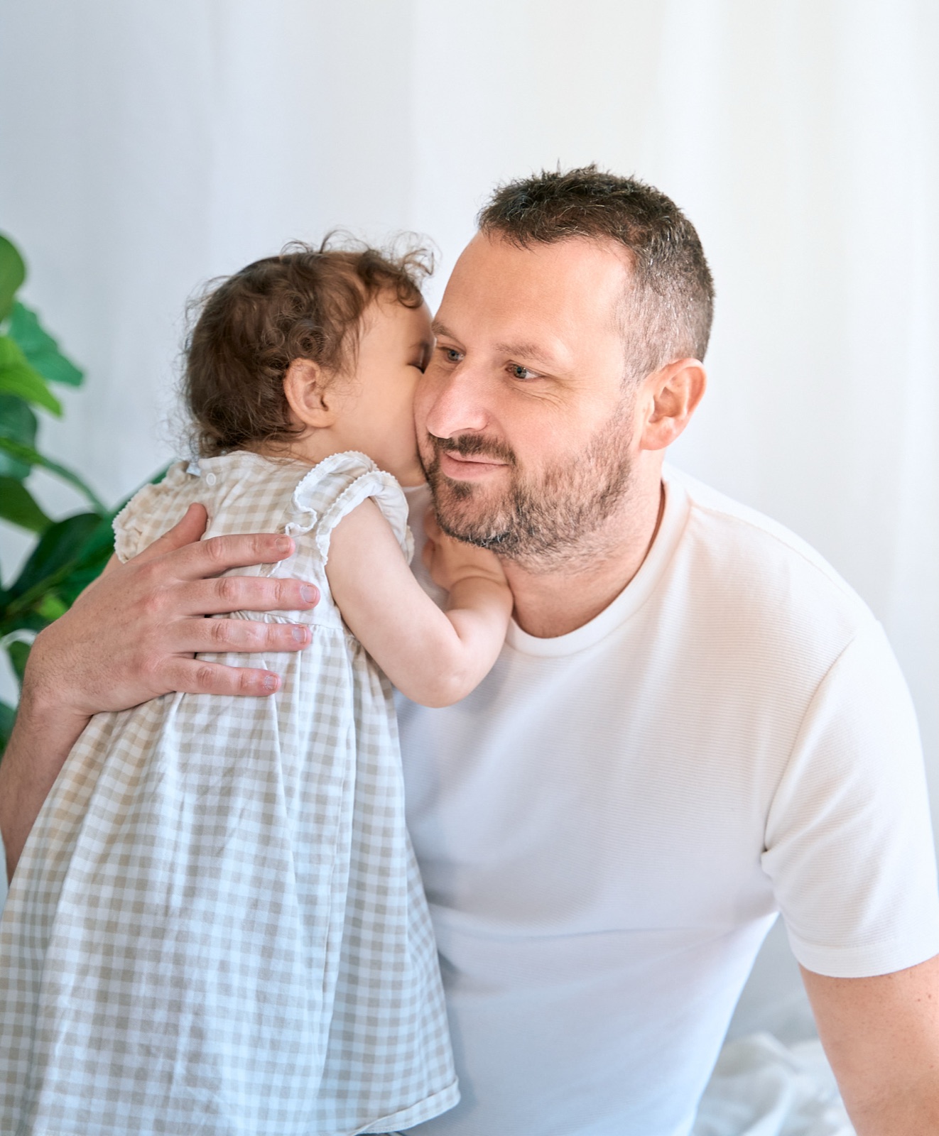 Dad holding his little girl as she kisses his forehead