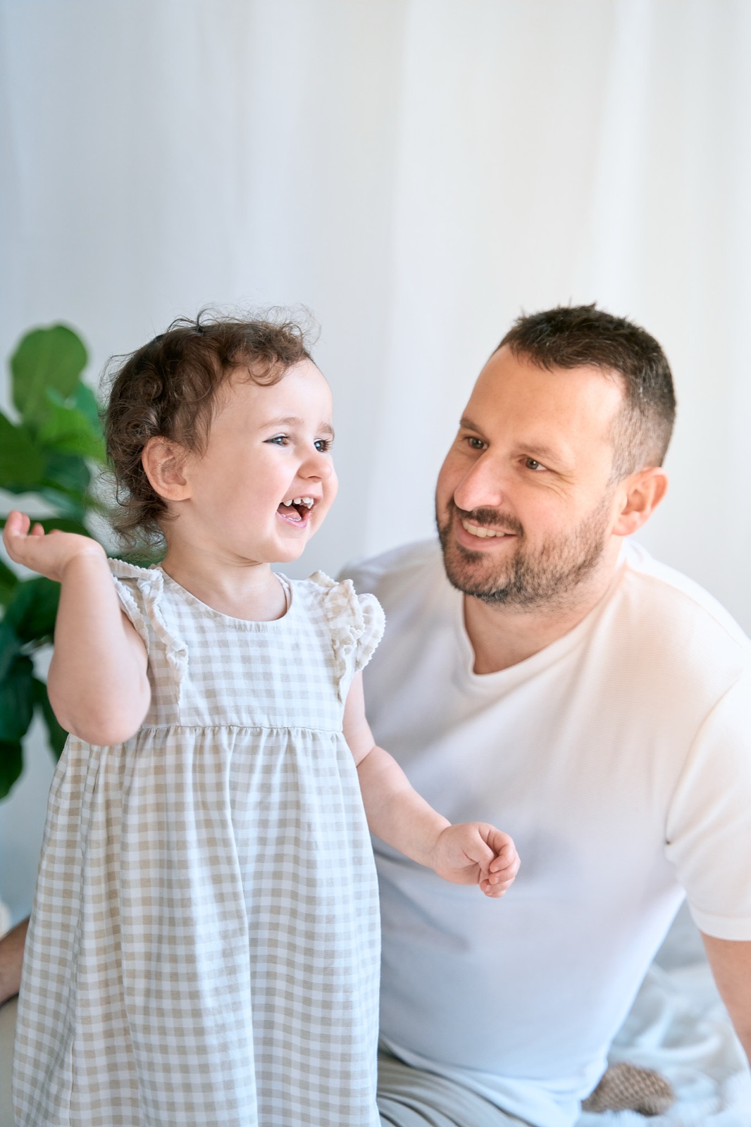 Toddler kissing dad's cheek, soft white bedroom session