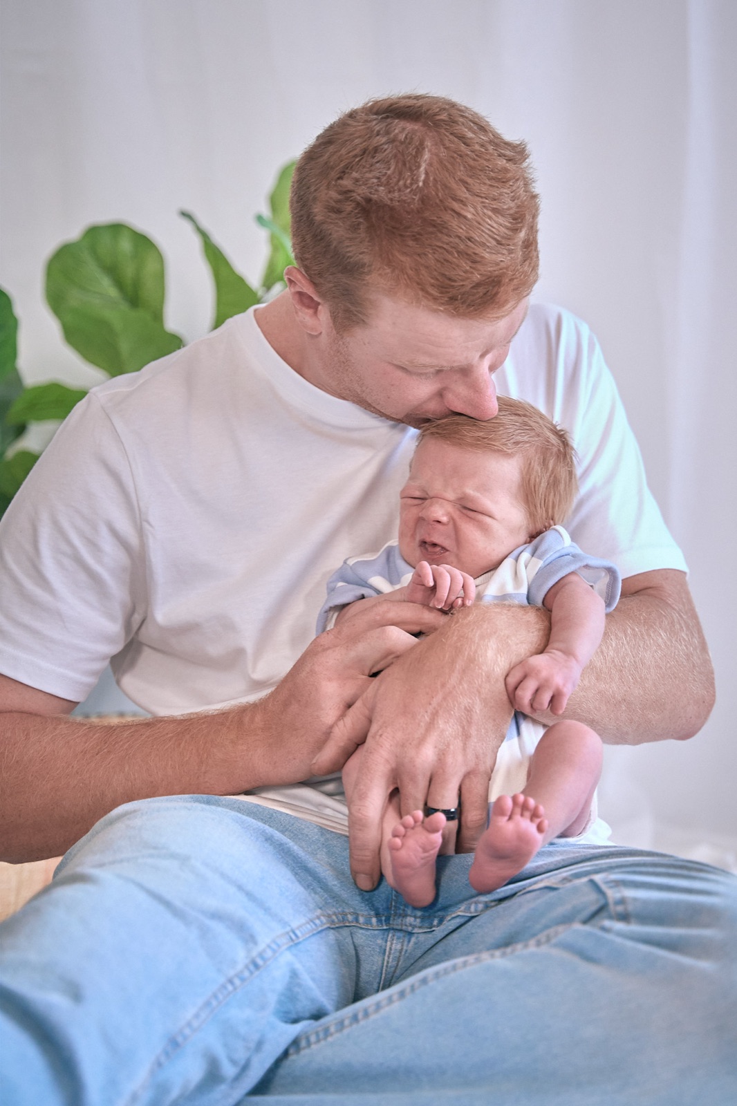 Dad cradling his newborn by the window