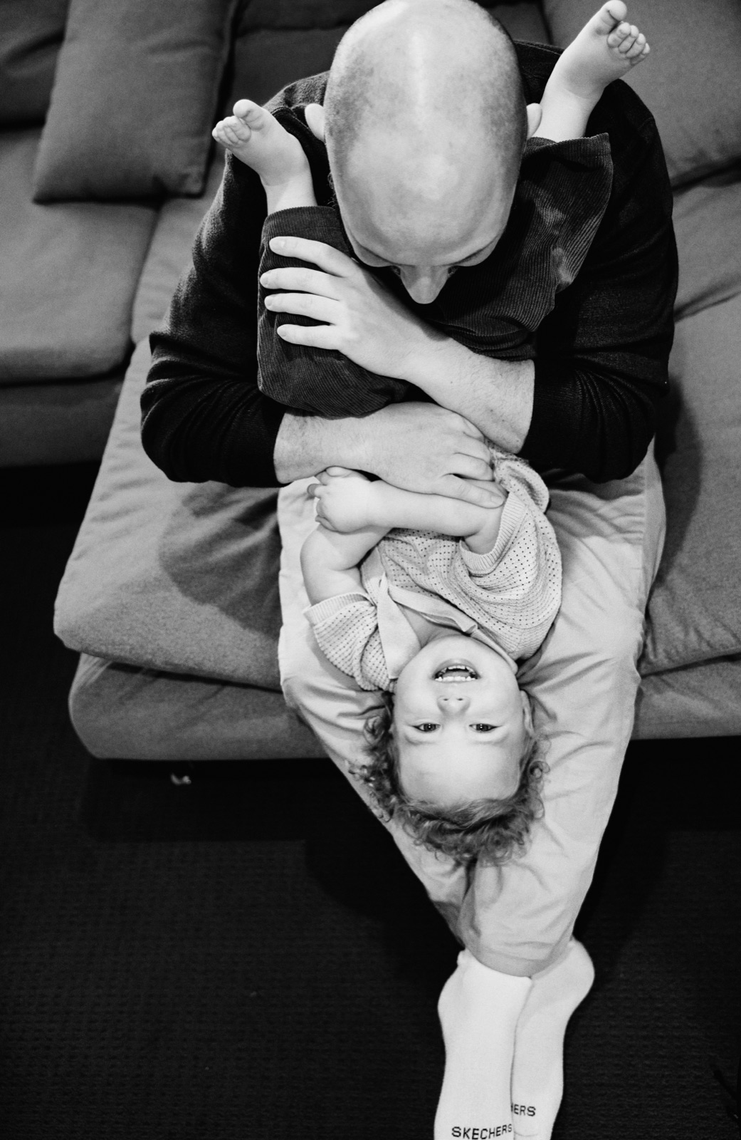 Dad holding his giggling toddler upside down