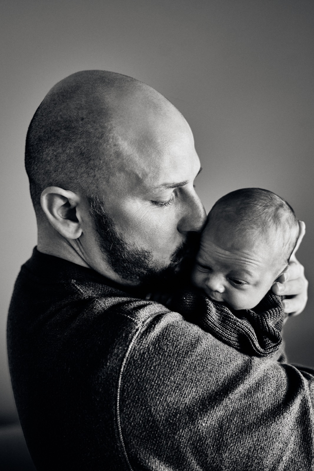 Black and white photo of dad holding his newborn against his chest