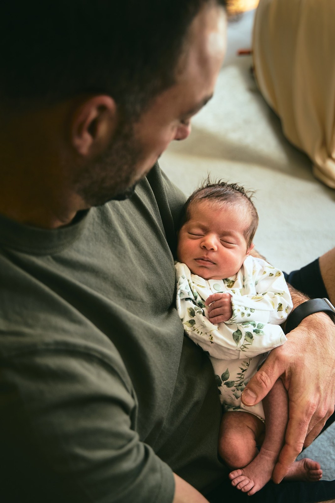 Dad cradling his newborn in the crook of his arm