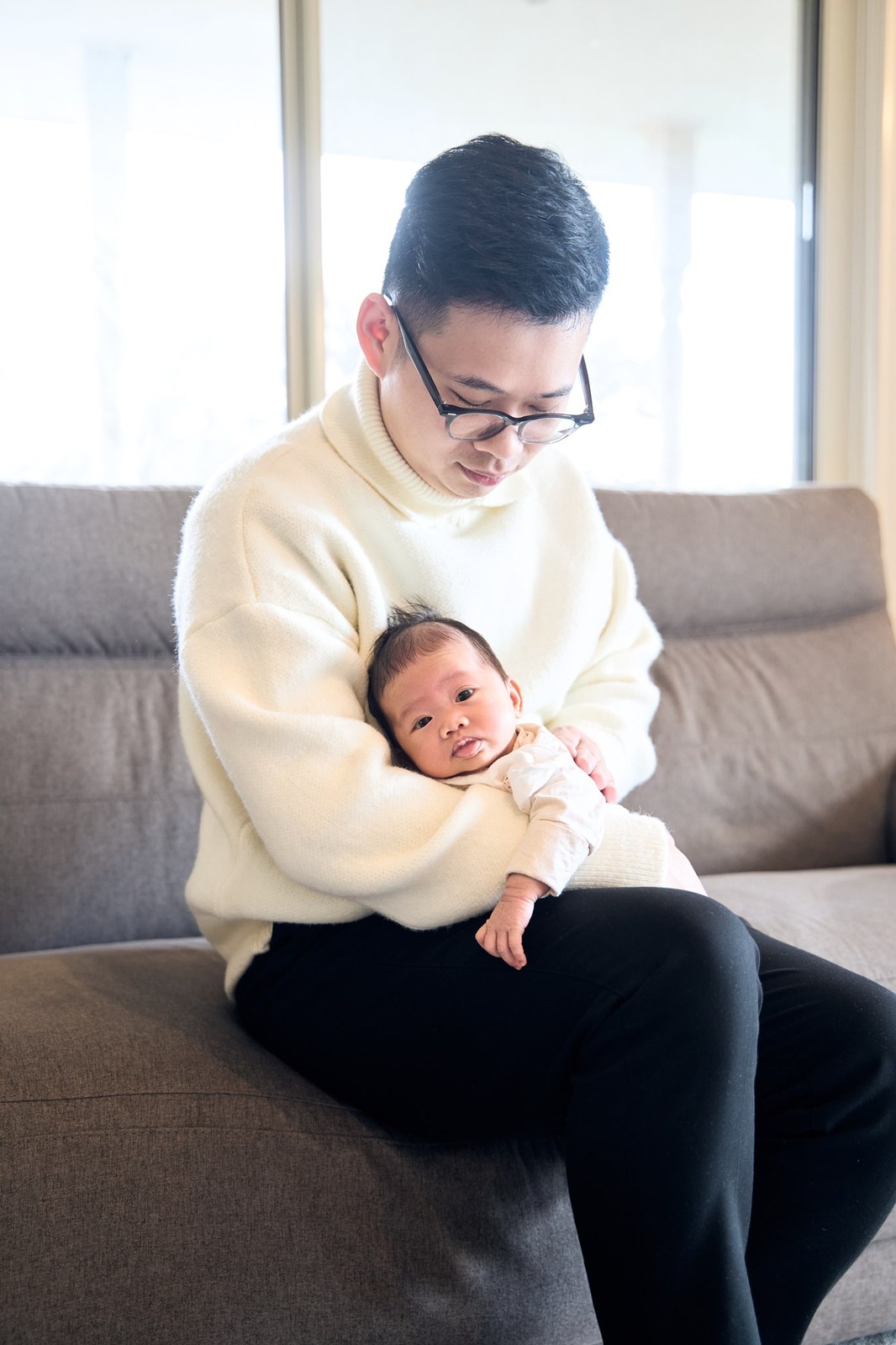 Dad on the couch with his newborn asleep against his chest