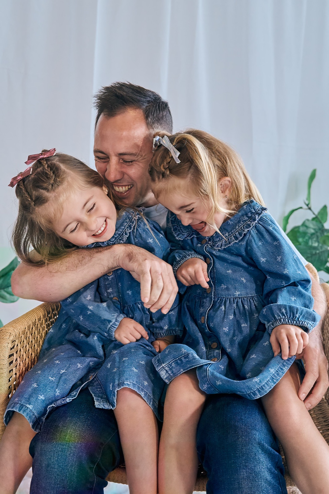Dad wrangling his two daughters in for a cuddle