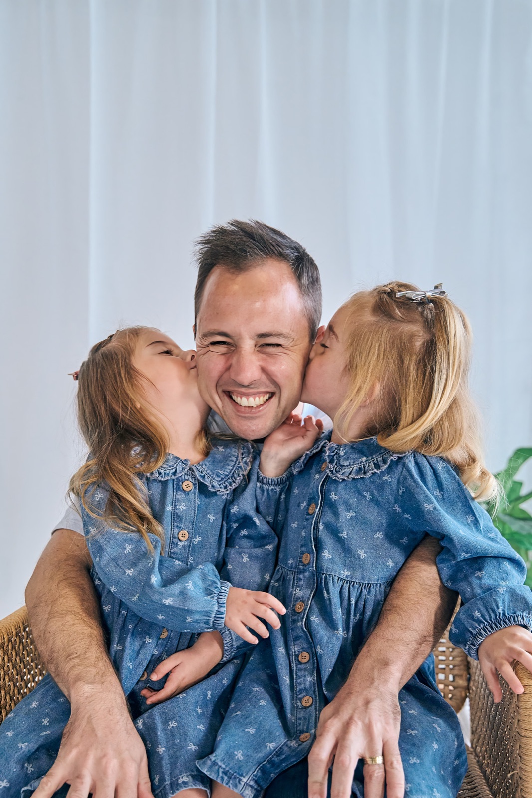 Dad with his two daughters in matching denim on his lap