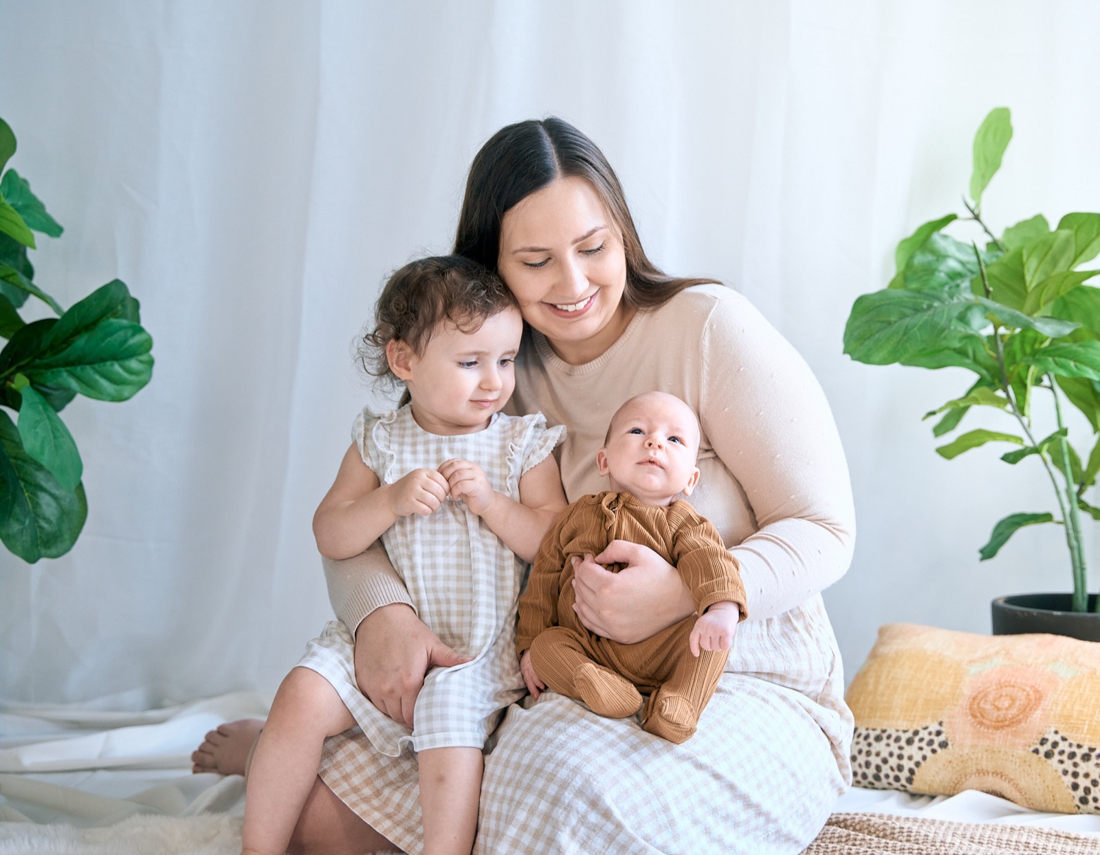 Mum holding her baby with a teddy bear, in-home motherhood session