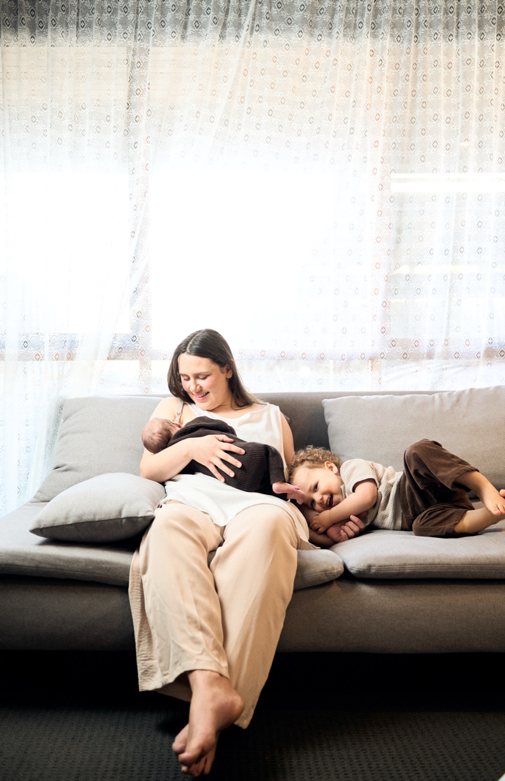 Mum cradling her baby on the couch by the window