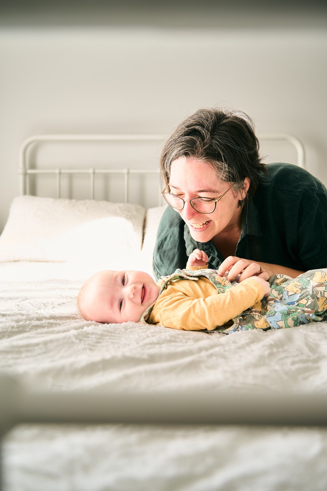 Mum leaning over her baby on the bed during an in-home session