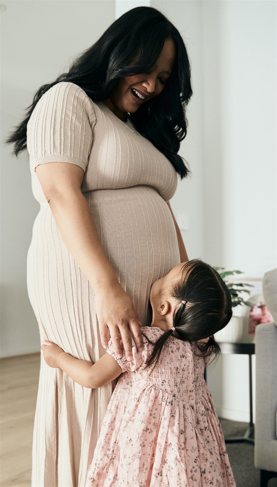 Expecting mum holding her bump with her toddler beside her, maternity session