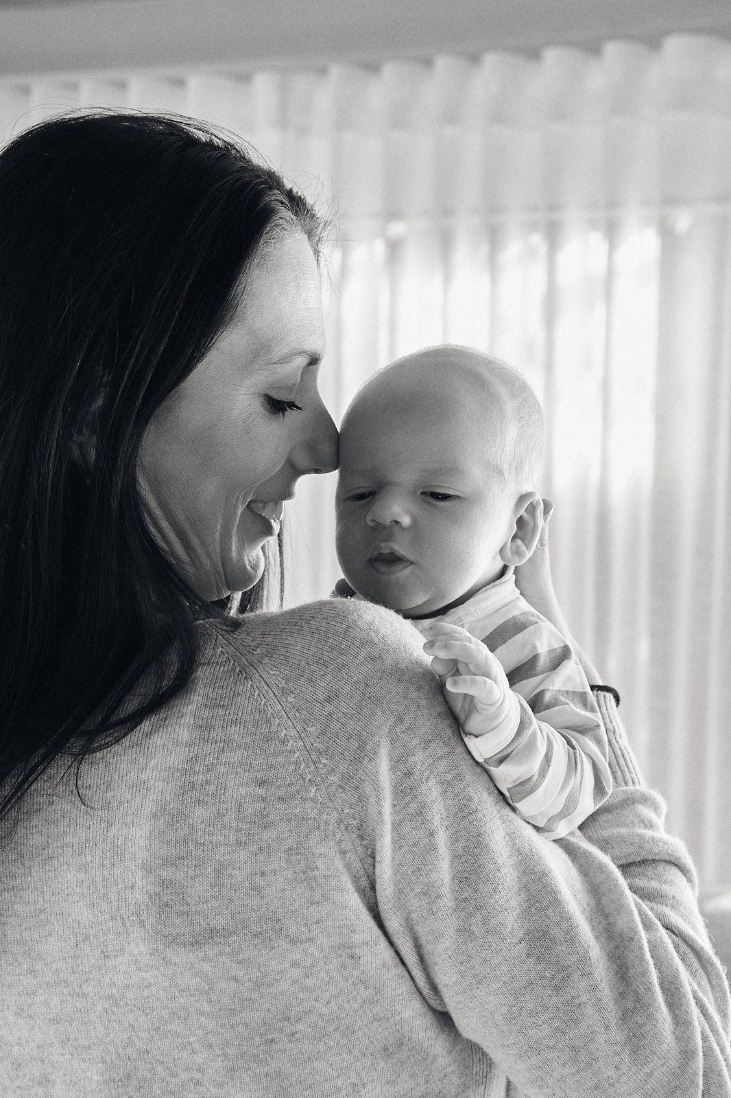 Black and white portrait of a mum holding her baby over her shoulder