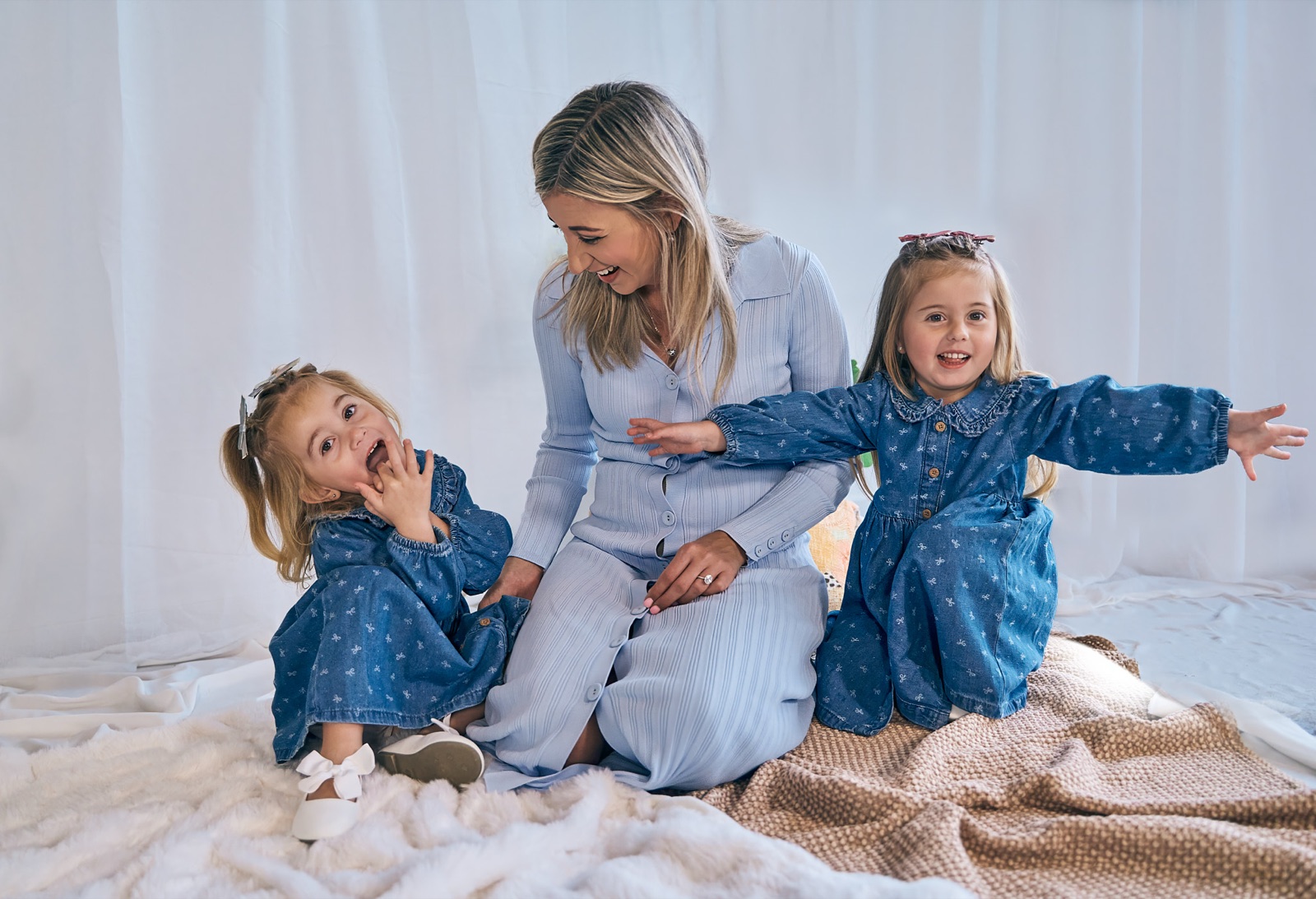 Mum playing on the bed with her two girls