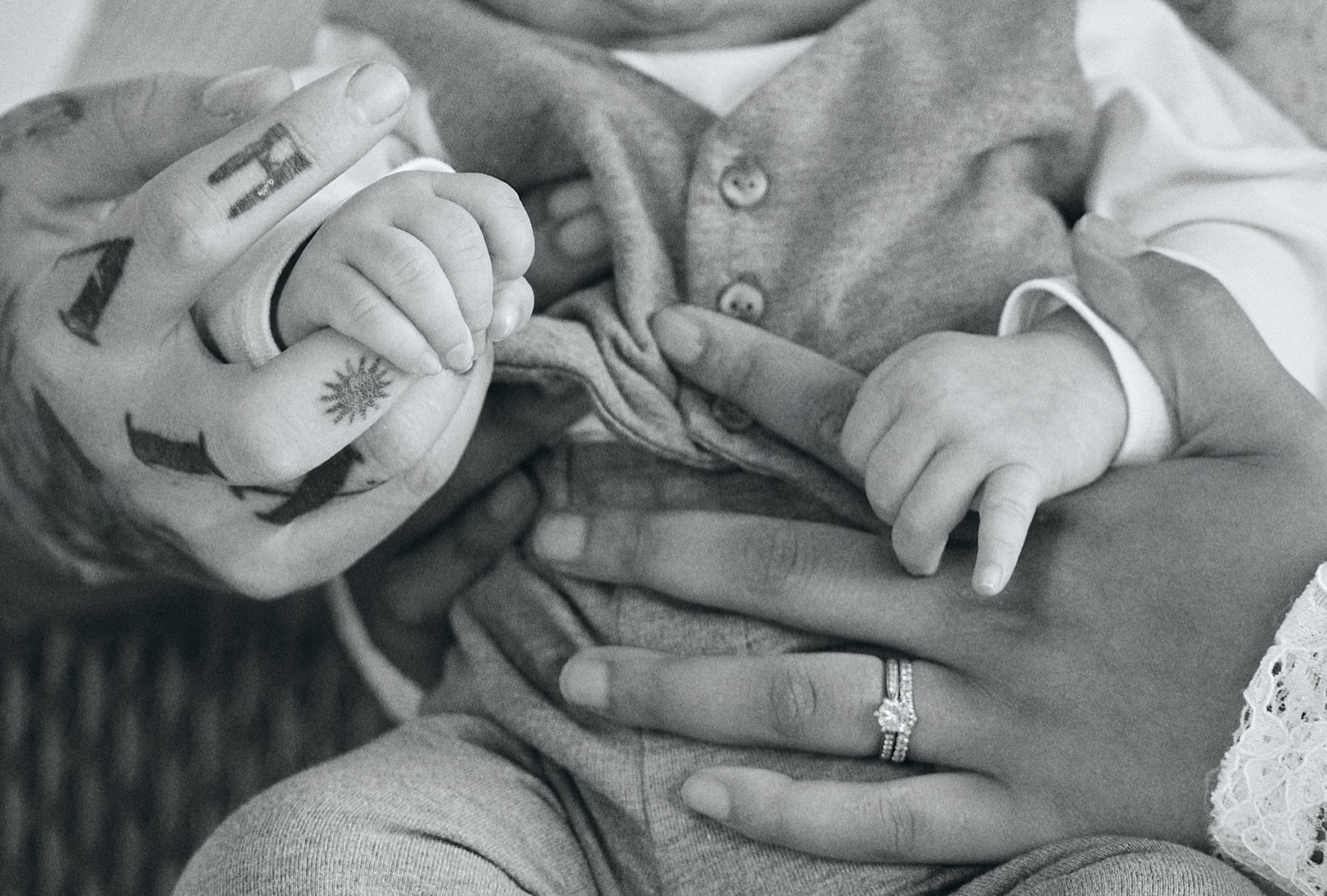 Family hands entwined around the newborn, black and white detail
