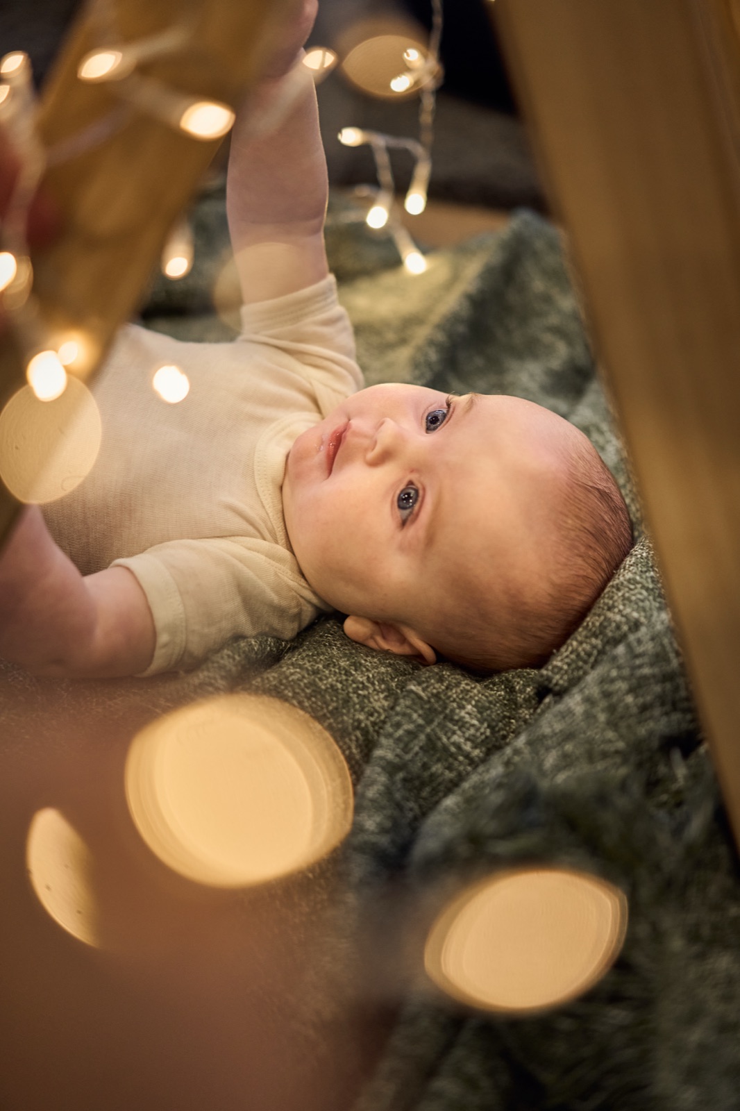 Newborn gazing up through golden fairy-light bokeh