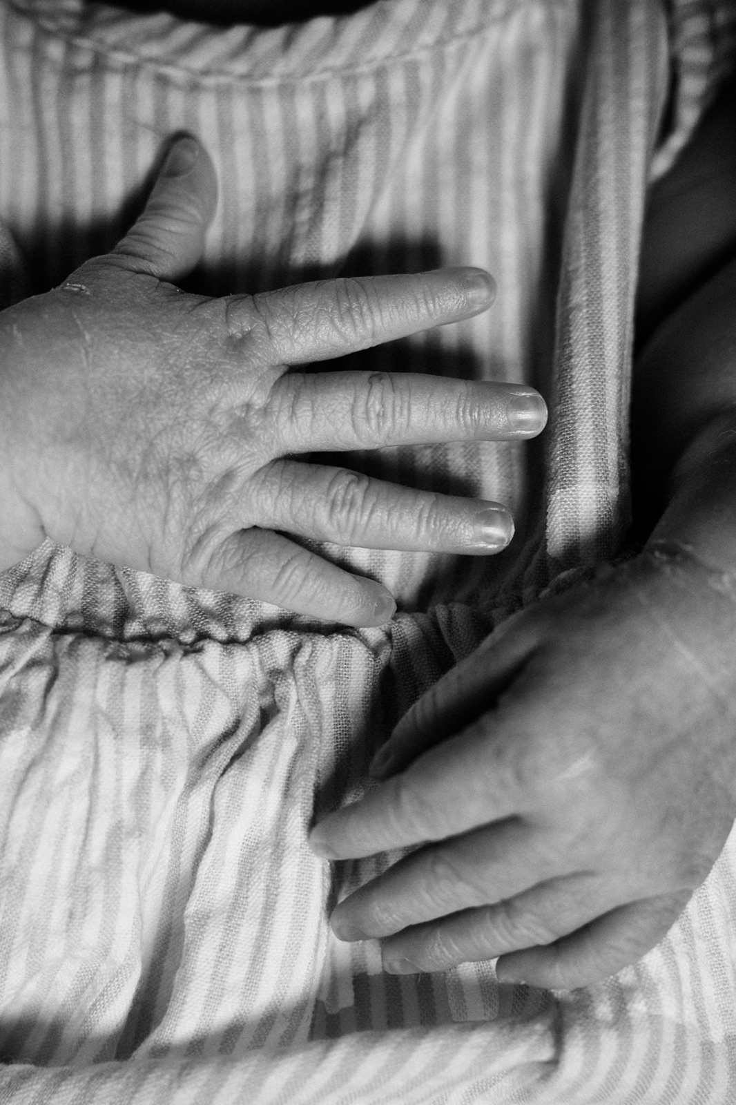 Newborn's hand resting on dad's hand, black and white detail