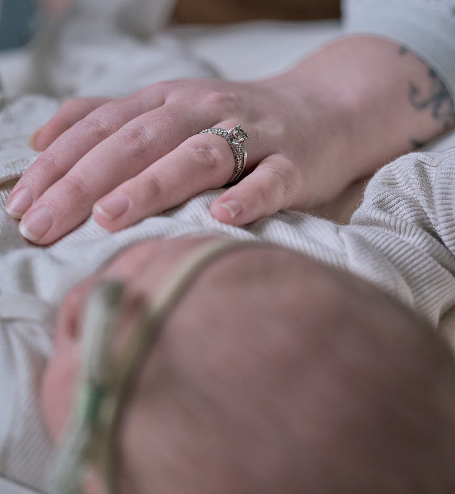 Parents' hands resting gently on their newborn's back