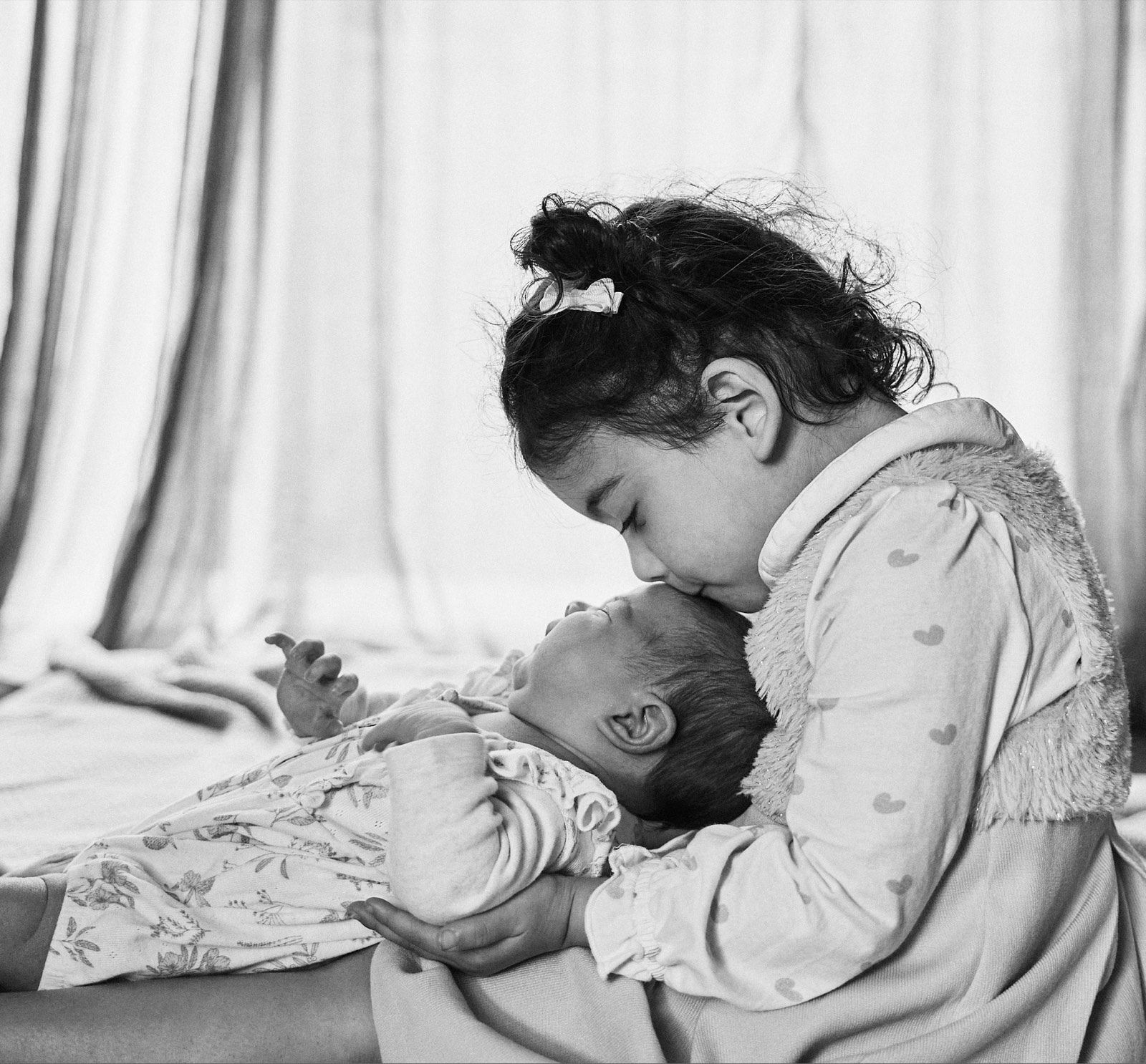 Mum leaning over her newborn on the bed, quiet morning moment