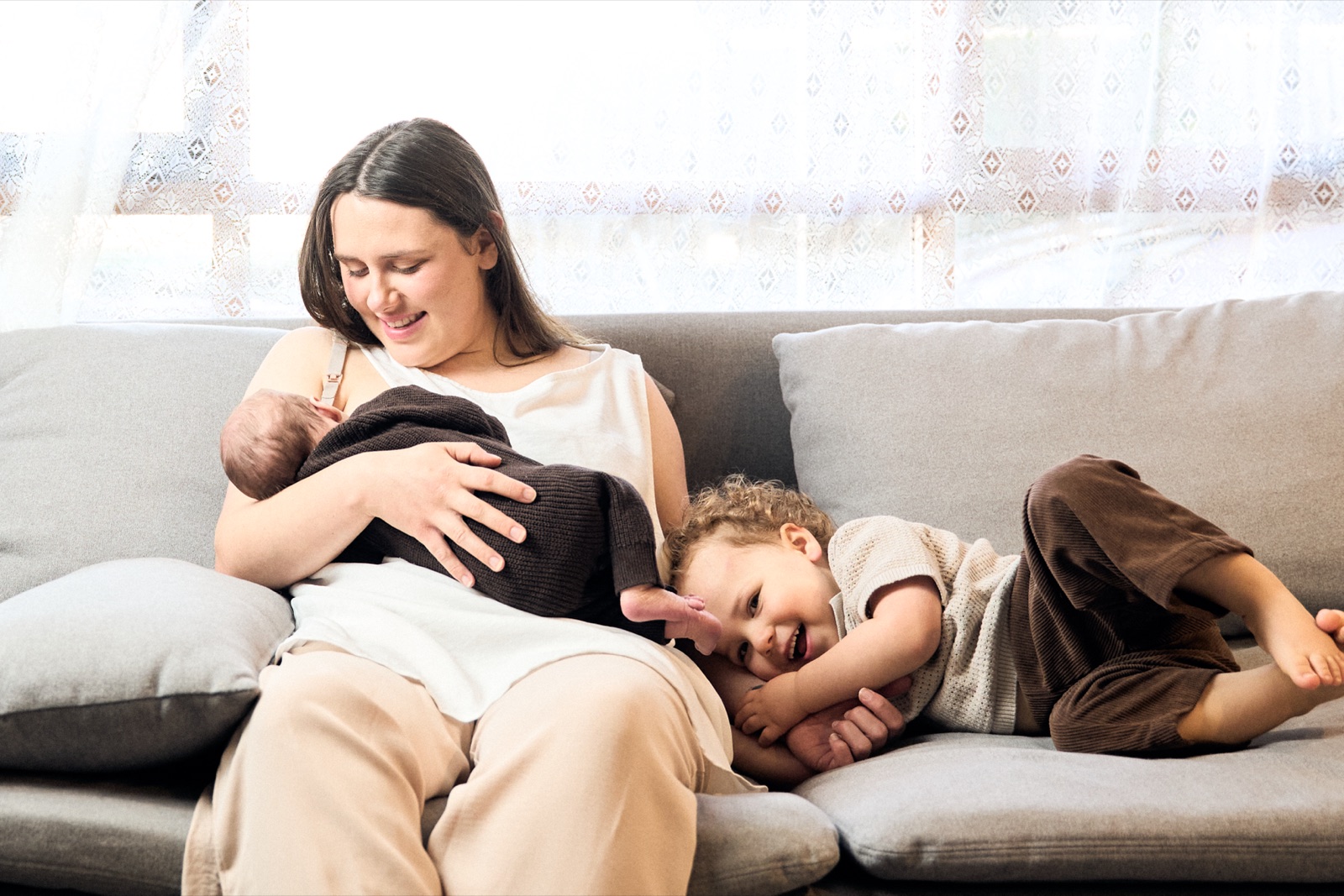Mum resting on the couch with her newborn and toddler, in-home session Chelsea