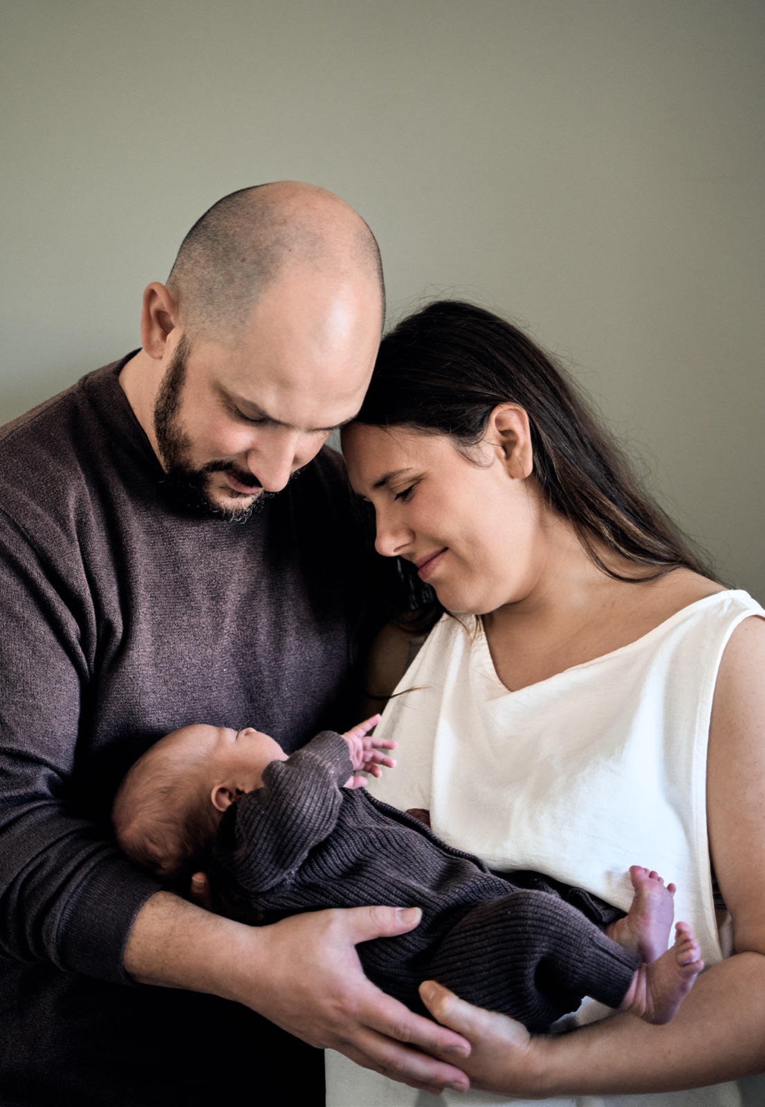 Parents cradling their newborn, fine art in-home portrait