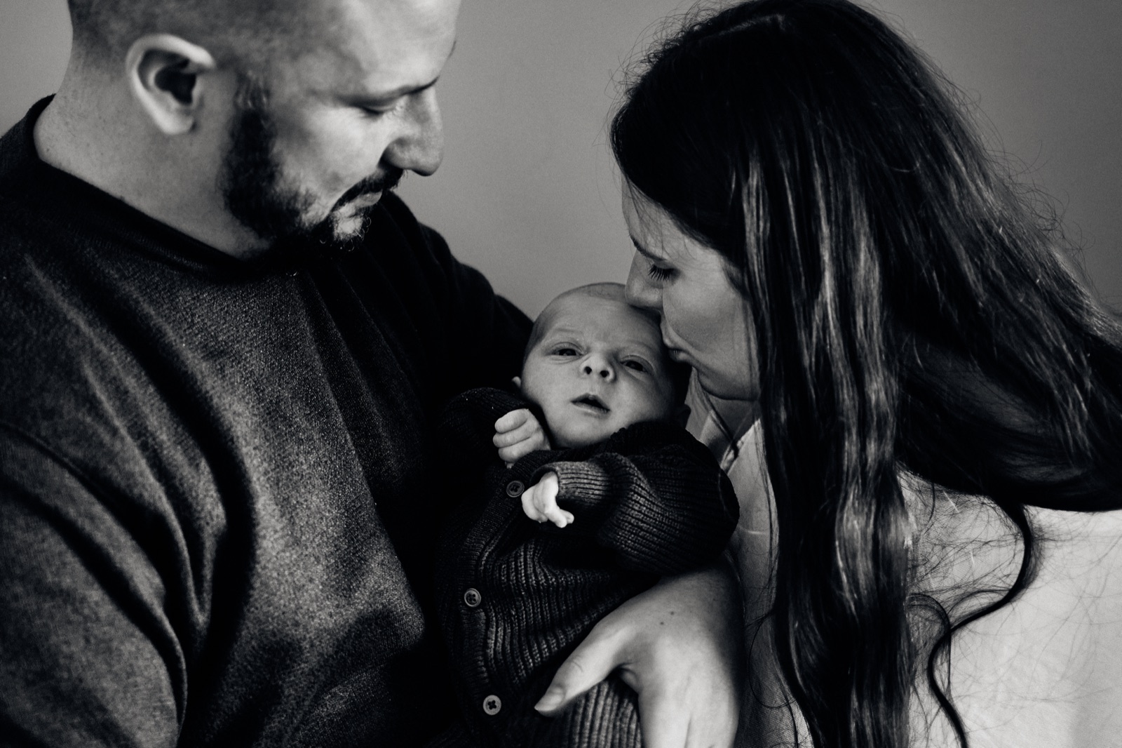 Black and white moment of parents holding their newborn close