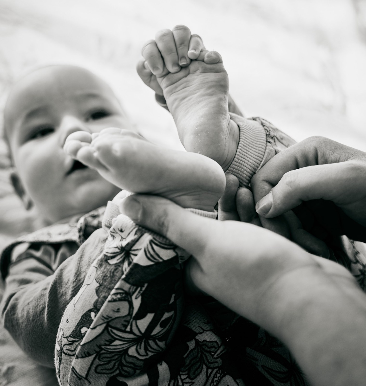 Black and white photo of a baby holding onto his own foot