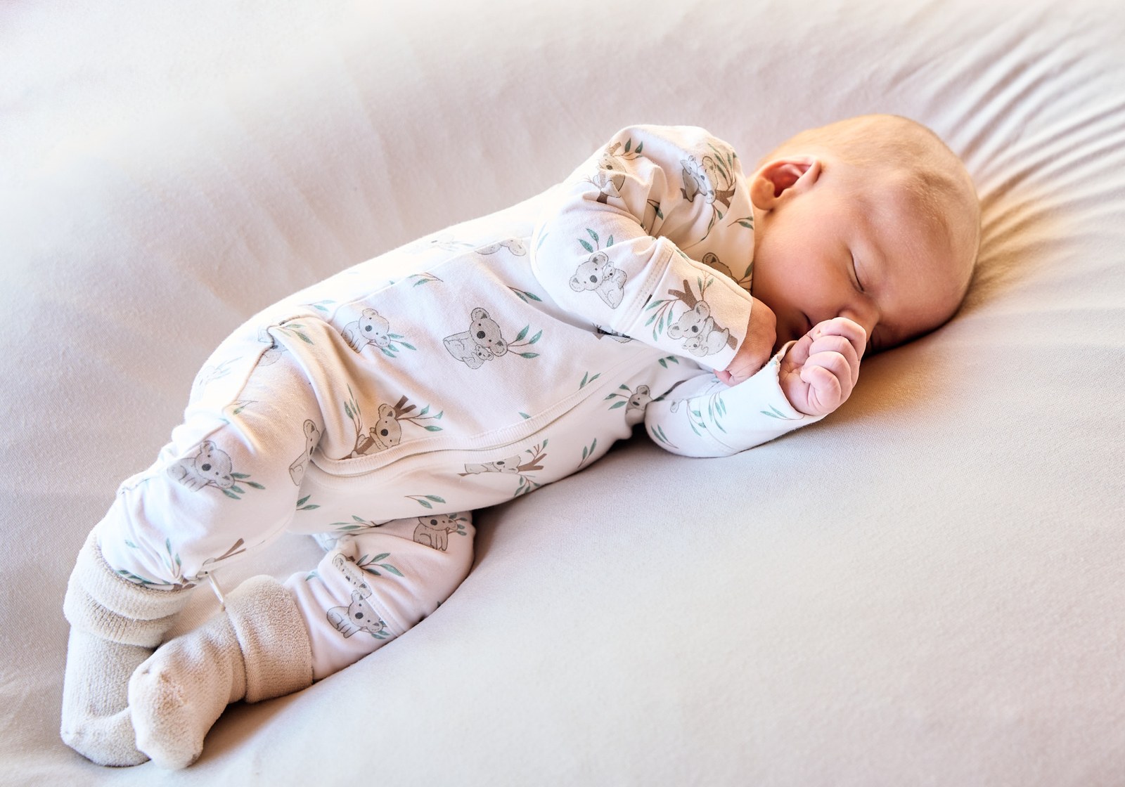 Newborn asleep on her side in a floral onesie