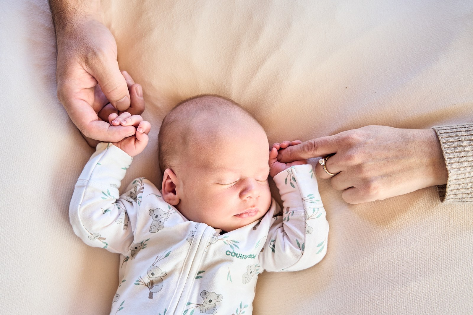 Each parent holding one of their newborn's hands