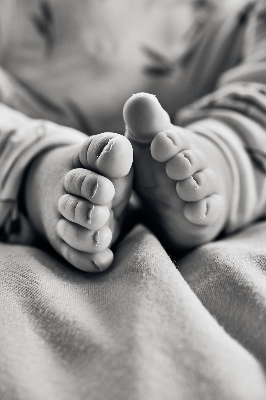 Black and white close-up of a newborn's hand and feet together