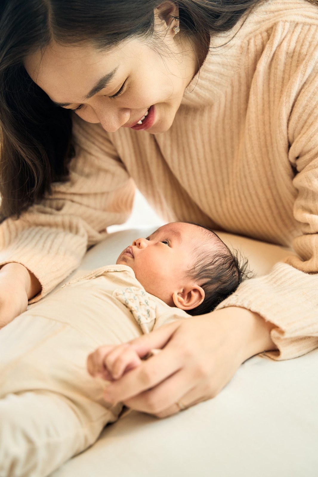 Mum lying beside her newborn on the bed, talking to her